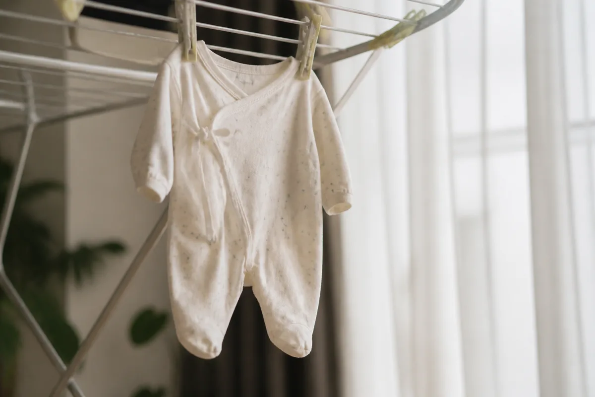 Pyjama de bébé suspendu à sécher à l&rsquo;air libre près d&rsquo;une fenêtre lumineuse